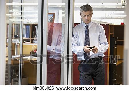Stock Photograph - Caucasian businessman text messaging on cell phone. Fotosearch