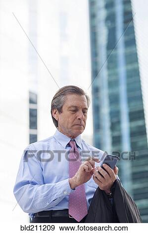Caucasian businessman using cell phone outside highrise View Large Photo Image Stock Photo - Caucasian businessman using cell phone outside highrise. Fotosearch