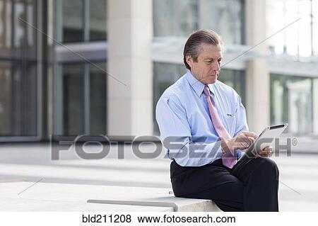 Caucasian businessman using digital tablet in courtyard View Large Photo Image Stock Photo - Caucasian businessman using digital tablet in courtyard. Fotosearch