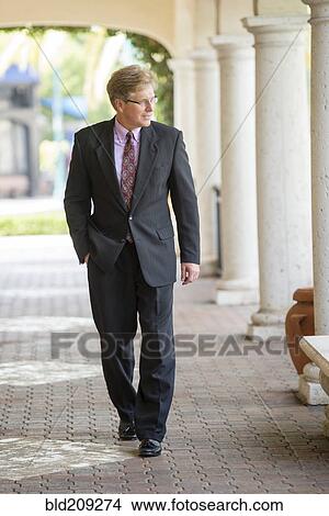 Picture - Caucasian businessman walking in colonnade. Fotosearch