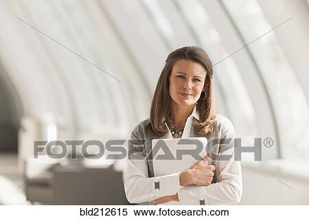 Stock Photography - Caucasian businesswoman carrying papers in lobby. Fotosearch