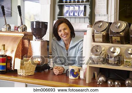 Stock Image - Caucasian cafe owner leaning on counter. Fotosearch