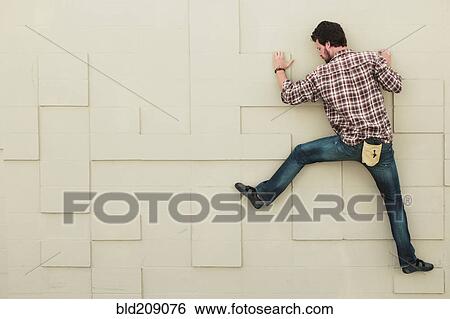 Stock Photograph - Caucasian climber scaling geometric wall. Fotosearch