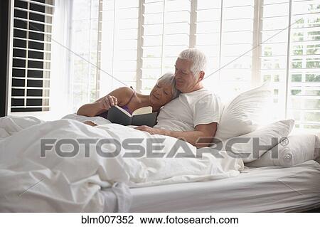 Caucasian couple cuddling in bed and reading book View Large Photo Image Stock Image - Caucasian couple cuddling in bed and reading book. Fotosearch