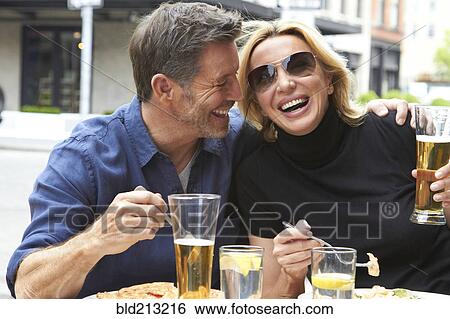 Stock Photograph - Caucasian couple drinking and eating at sidewalk cafe. Fotosearch