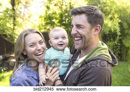 Stock Photography - Caucasian couple holding baby in backyard. Fotosearch