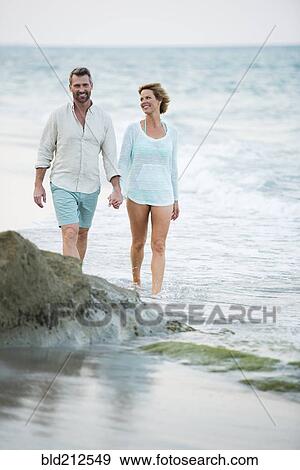 Stock Photo - Caucasian couple holding hands on beach. Fotosearch