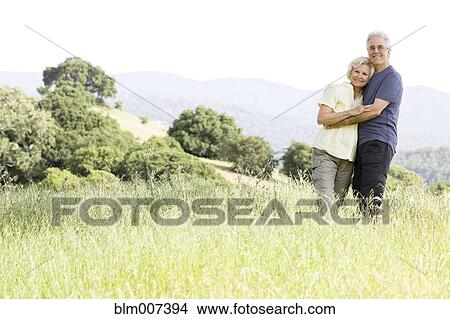 Picture - Caucasian couple hugging in field. Fotosearch