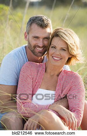Stock Photograph - Caucasian couple hugging in tall grass. Fotosearch