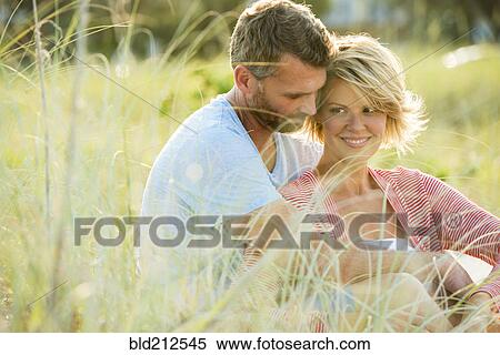 Stock Photography - Caucasian couple hugging in tall grass. Fotosearch
