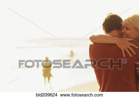 Picture - Caucasian couple hugging on beach. Fotosearch