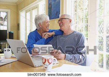 Caucasian couple laughing and using laptop View Large Photo Image Stock Photo - Caucasian couple laughing and using laptop. Fotosearch