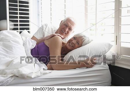 Caucasian couple laying in bed smiling View Large Photo Image Stock Image - Caucasian couple laying in bed smiling. Fotosearch
