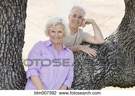Stock Image - Caucasian couple leaning on tree. Fotosearch