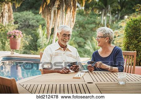 Stock Photo - Caucasian couple playing cards outdoors. Fotosearch