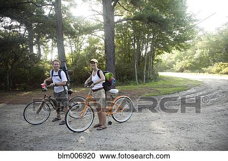 Stock Image - Caucasian couple riding bikes on dirt road. Fotosearch