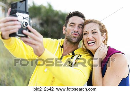 Stock Image - Caucasian couple taking self-portrait with vintage camera. Fotosearch