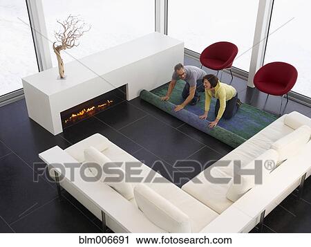 Caucasian couple unrolling carpet in modern living room View Large Photo Image Stock Image - Caucasian couple unrolling carpet in modern living room. Fotosearch