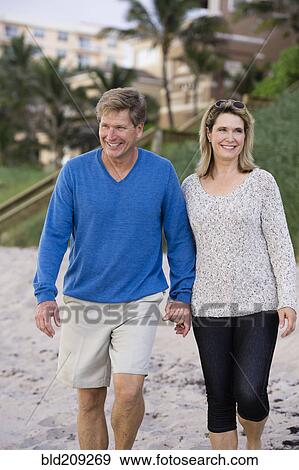 Stock Photo - Caucasian couple walking on beach. Fotosearch