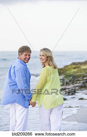 Stock Photograph - Caucasian couple walking on beach. Fotosearch