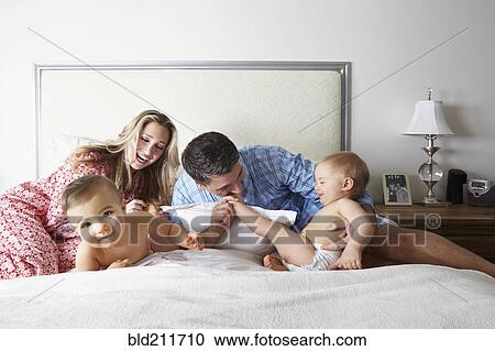 Stock Image - Caucasian family playing on bed. Fotosearch