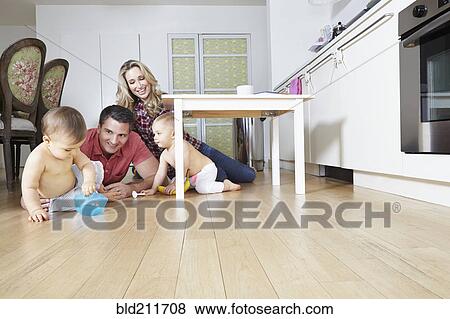 Stock Photo - Caucasian family playing on kitchen floor. Fotosearch