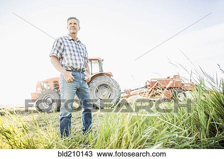 Stock Image - Caucasian farmer standing in field. Fotosearch