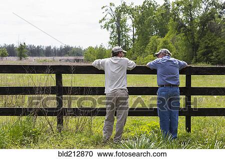 Caucasian father and son leaning on fence by rural field View Large Photo Image Stock Image - Caucasian father and son leaning on fence by rural field. Fotosearch