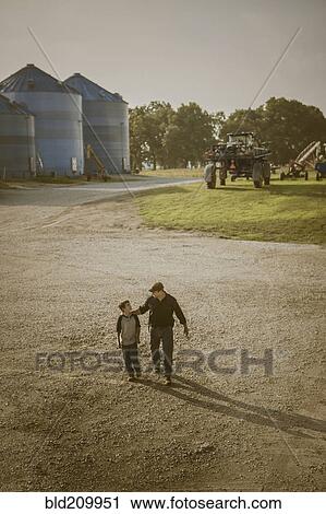 Stock Image - Caucasian father and son walking on farm. Fotosearch