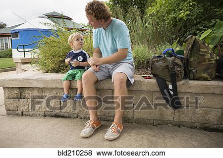 Caucasian father and toddler son sitting in park View Large Photo Image Stock Photo - Caucasian father and toddler son sitting in park. Fotosearch
