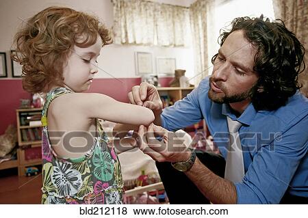 Stock Photo - Caucasian father examining daughter's scrape. Fotosearch