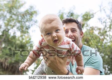Caucasian father playing with baby outdoors View Large Photo Image Stock Photo - Caucasian father playing with baby outdoors. Fotosearch