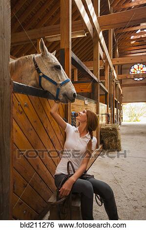 Caucasian girl petting horse in stable View Large Photo Image Stock Photograph - Caucasian girl petting horse in stable. Fotosearch