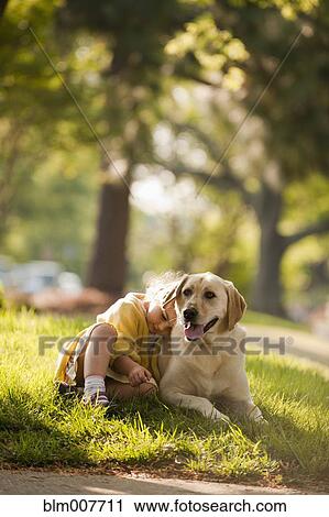 Stock Image - Caucasian girl playing with dog in yard. Fotosearch