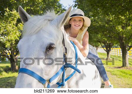 Stock Photo - Caucasian girl riding horse on dirt path. Fotosearch