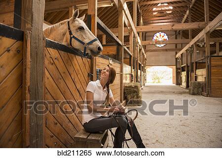 Caucasian girl sitting with horse in stable View Large Photo Image Stock Photography - Caucasian girl sitting with horse in stable. Fotosearch