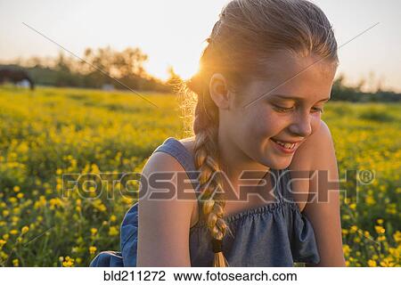 Stock Image - Caucasian girl smiling in field of flowers. Fotosearch