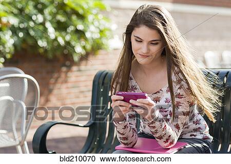 Stock Image - Caucasian girl using cell phone outdoors. Fotosearch