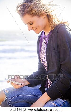 Stock Image - Caucasian girl using cell phone outdoors. Fotosearch