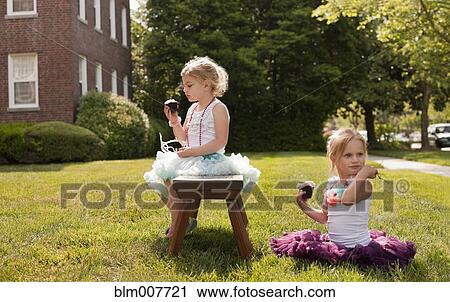 Stock Image - Caucasian girls playing dress up in yard. Fotosearch
