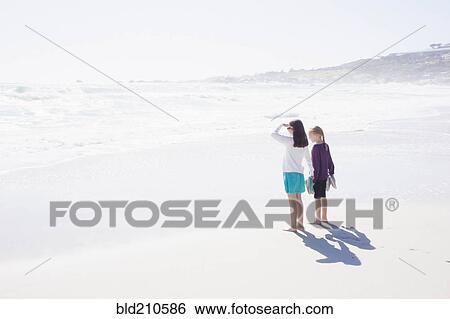Stock Photograph - Caucasian girls standing on bright beach. Fotosearch