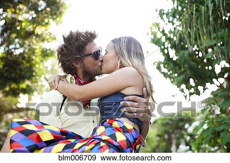 Stock Photo - Caucasian man carrying and kissing girlfriend. Fotosearch