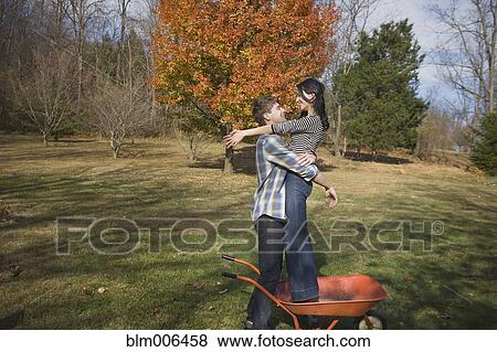 Caucasian man hugging girlfriend in yard View Large Photo Image Stock Photo - Caucasian man hugging girlfriend in yard. Fotosearch