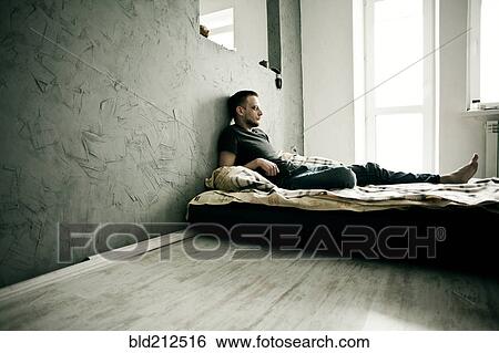 Stock Photograph - Caucasian man laying on bed. Fotosearch