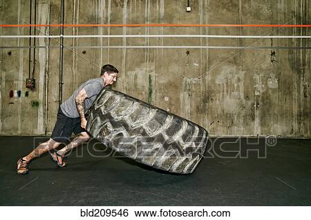 Caucasian man lifting large tire in gym View Large Photo Image Stock Photograph - Caucasian man lifting large tire in gym. Fotosearch