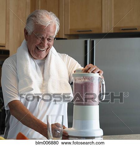 Stock Image - Caucasian man making smoothie in kitchen. Fotosearch