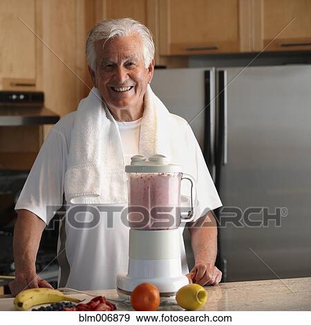 Stock Photo - Caucasian man making smoothie in kitchen. Fotosearch