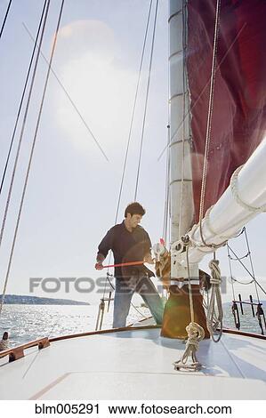 Stock Image - Caucasian man on sailboat. Fotosearch