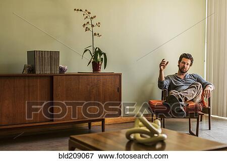 Stock Photo - Caucasian man relaxing in living room. Fotosearch