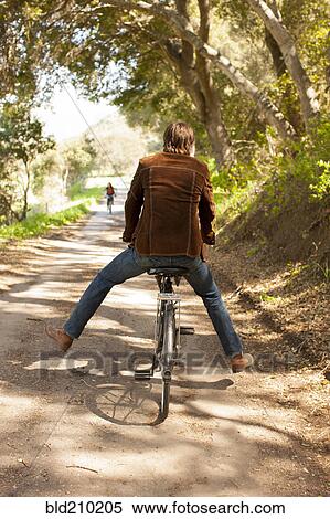 Caucasian man riding bicycle on rural road View Large Photo Image Stock Photography - Caucasian man riding bicycle on rural road. Fotosearch